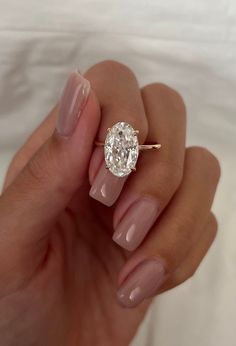 a woman's hand holding a ring with a large diamond on the middle of it