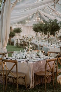 an outdoor tent with tables and chairs set up for a formal dinner or wedding reception