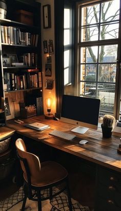 a desk with a computer on top of it in front of a window filled with books