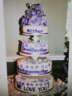 three tiered cake with purple and white flowers on the bottom layer that says, i love you