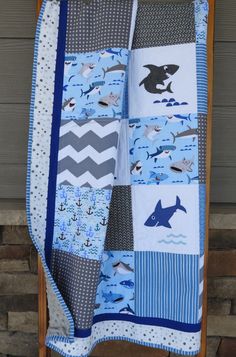 a baby quilt is hanging on a clothes rack in front of a door with an ocean theme