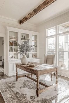 a dining room table and chairs in front of large windows with open shelving on either side