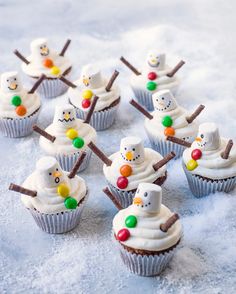 cupcakes decorated with frosting and candy are sitting in the snow