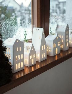 small white houses are sitting on a window sill in front of the windowsill