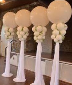 balloons and flowers are arranged in tall white vases