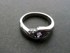 a silver ring with an amethorate stone in the center on a black surface