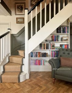 a chair sitting in front of a book shelf under a stair case