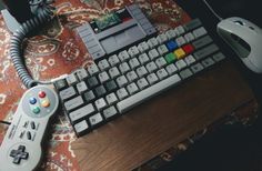 a computer keyboard, mouse and controller sitting on a table next to a carpeted rug