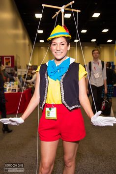 a woman dressed in costume and holding two strings attached to her head while standing on the floor