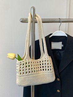 a crocheted bag hanging on a coat rack with a tulip in it