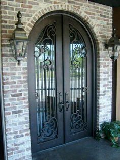 the front door to a home with wrought iron doors and sidelights on either side