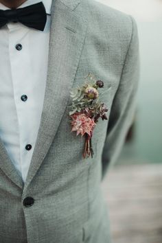 a man wearing a suit and bow tie with a boutonniere on his lapel