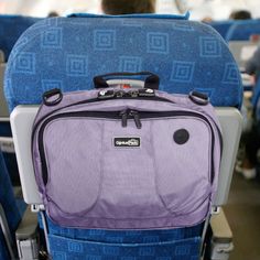 the back end of an airplane seat with a purple bag on it