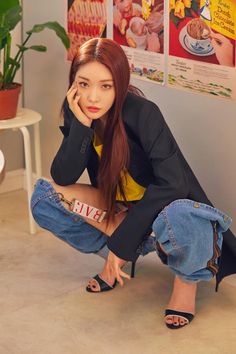 a young woman sitting on the floor with her hand to her face and looking at the camera