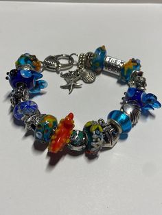 a colorful bracelet with charms on it sitting on a table next to a bottle opener