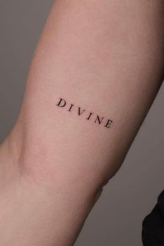 a woman's arm with the word divine tattooed on her left arm, in black ink