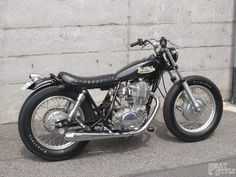 a black motorcycle parked next to a wall