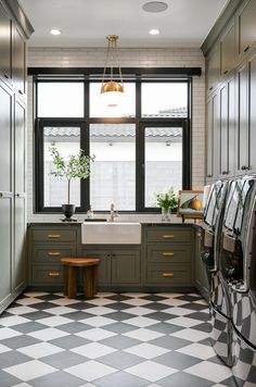 a kitchen with black and white checkered flooring, green cabinets and an open window