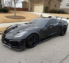 a black sports car parked in front of a house