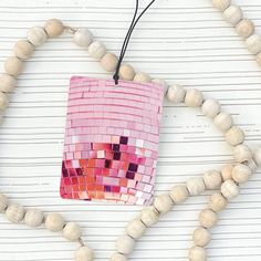 a wooden bead necklace with a pink bag hanging from it's side on a white background