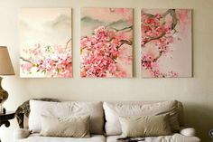 three paintings hang on the wall above a couch in a living room with white furniture