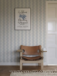 a chair sitting in front of a wall with a sign on the wall above it