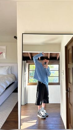 a man standing in front of a mirror on top of a wooden floor