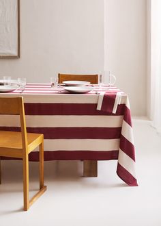 the table is set with two plates on it, and one has a striped cloth draped over it