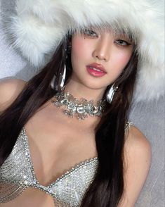 a woman with long dark hair wearing a silver dress and fur hat on top of her head