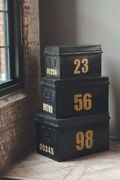 three black boxes sitting next to each other in front of a brick wall with numbers on them