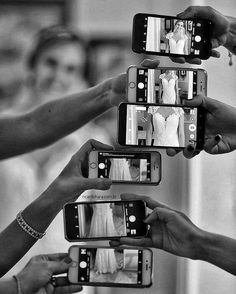 four people holding up their cell phones to take pictures with the brides wedding dress