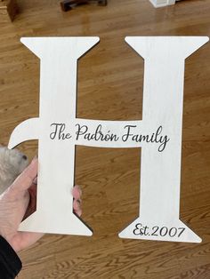 a person holding up a wooden sign with the letters h and j on it in front of a wood floor