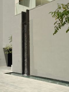 a tall white building sitting next to a planter filled with green leaves on the side of it