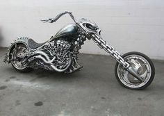 a silver motorcycle parked in front of a white wall with chains on it's side