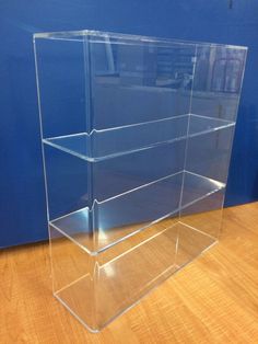 a clear acrylic box sitting on top of a wooden floor next to a blue wall