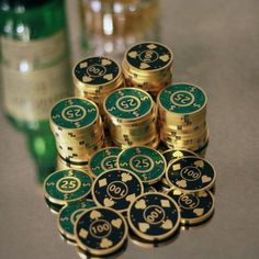 stacks of gold and green poker chips next to a bottle