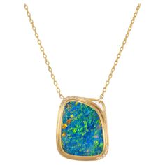 Australian boulder opal of strong blue and green color, accented with red flashes. 4.85ct freeform opal mounted in a handmade 22k yellow gold bezel and frame and accented with 13 full cut round diamonds. diamond accents. The boulder opal, with its unique play of colors, is beautifully complemented by the sparkling diamonds. 16 inch 22k yellow gold chain. 1 blue red green flash boulder opal, approx. 4.85cts 13 full cut round diamonds, F-G VS approx. .65cts 22k yellow gold Stamped: NTF 22k 11.5 gr Boulder Opal Necklace, Boulder Opal Pendant, Green Pendants, Opal Pendant Necklace, Australian Boulder Opal, Yellow Gold Setting, Modern Necklaces, Yellow Gold Chain, Yellow Gold Pendants