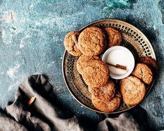 some cookies are on a plate with a glass of milk and cinnamon sticks in the middle