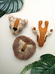 three stuffed animals sitting on top of a white table next to green plants and leaves