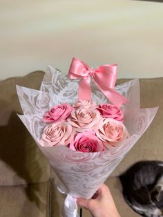 a person holding a bouquet of roses with a dog laying on the couch behind them