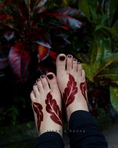 a woman's feet covered in hendi with red flowers on them and leaves