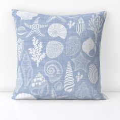 a blue and white pillow with shells on it