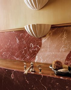 a bathroom with marble counter tops and gold accents on the walls, along with two bowls filled with pastries