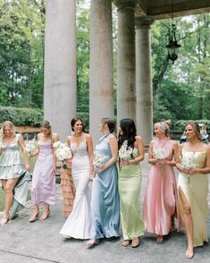 a group of women standing next to each other in front of some tall pillars with flowers