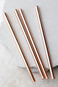 three copper straws sitting on top of a rock