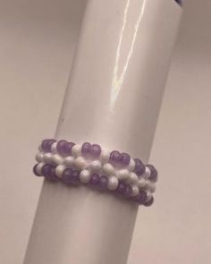 three bracelets with beads are sitting on a white pole in front of a blue tube