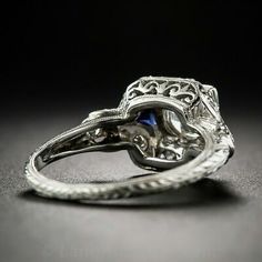 an antique style diamond and blue sapphire engagement ring in white gold with filigrees