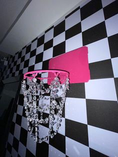 a pink chandelier hanging from the side of a black and white checkered wall