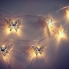 some fairy lights are hanging on the wall with butterfly shaped string lights attached to them