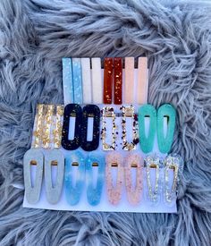 six pairs of hair clips in different colors and sizes on a furry surface with gold glitters